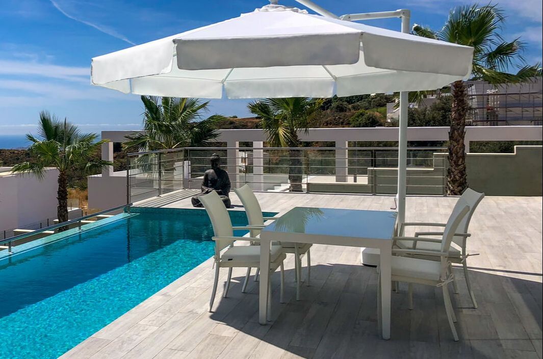 Cantilever umbrella in a pool terrace with white aluminium garden dining set with sea views in Fuengirola, Malaga, Costa del Sol, Spain