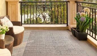 Terrace with outdoor carpet, iron veranda and two outdoor armchairs in an elegant villa in Sotogrande, cadiz, Spain