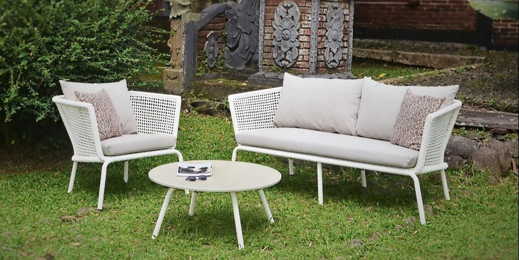Outdoor set of small sofa with armchair weaved rope and concrete coffee table in a balinese garden in Marbella